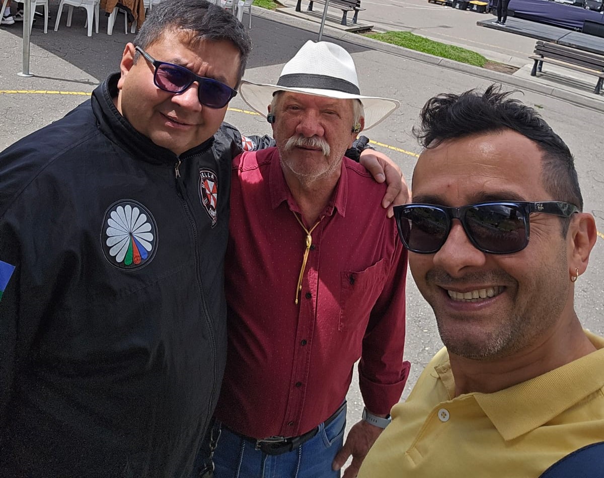 Hombre líder de la Fundación Gitanos de Colombia acompañado de tres mujeres ROM con vestidos tradicionales gitanos en un encuentro comunitario en Bogotá D.C.